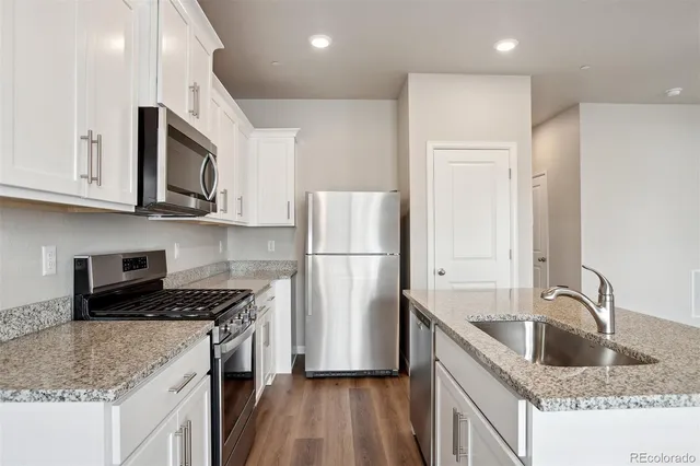 a kitchen with stainless steel appliances granite countertop a sink stove and refrigerator