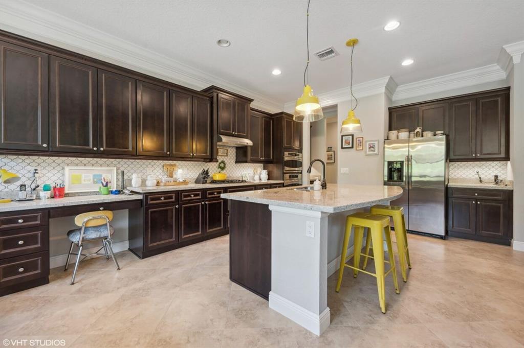 7619 Southeast Belle Maison Drive Stuart, FL 34997 - Photo 5 of 44 a kitchen with kitchen island granite countertop wooden cabinets and stainless steel appliances