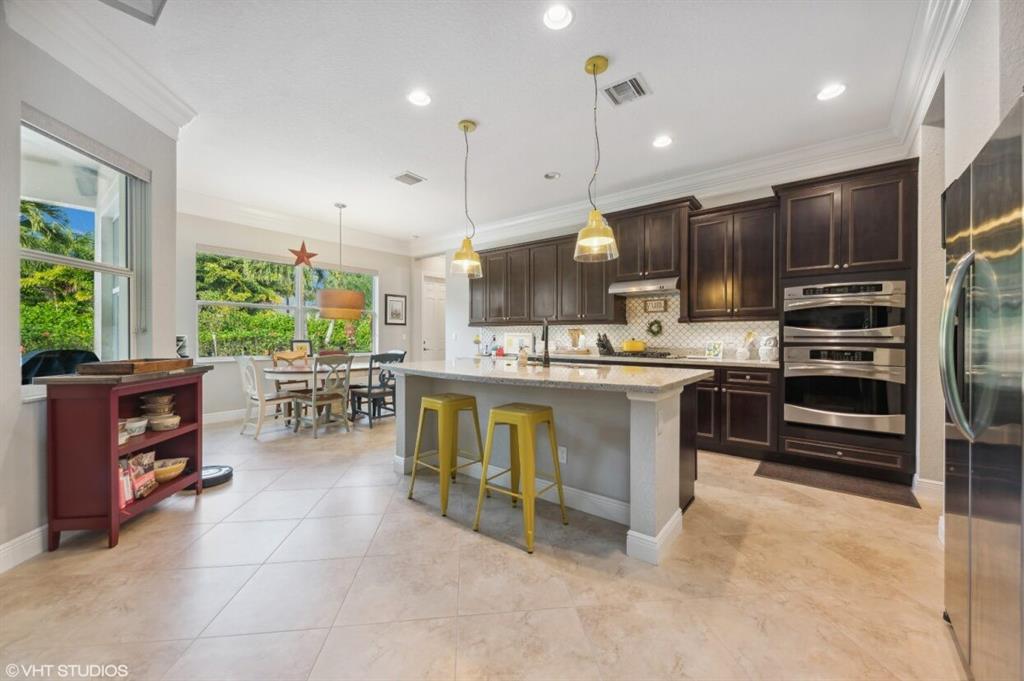 7619 Southeast Belle Maison Drive Stuart, FL 34997 - Photo 8 of 44 a kitchen with stainless steel appliances kitchen island granite countertop a stove a sink a oven and a refrigerator