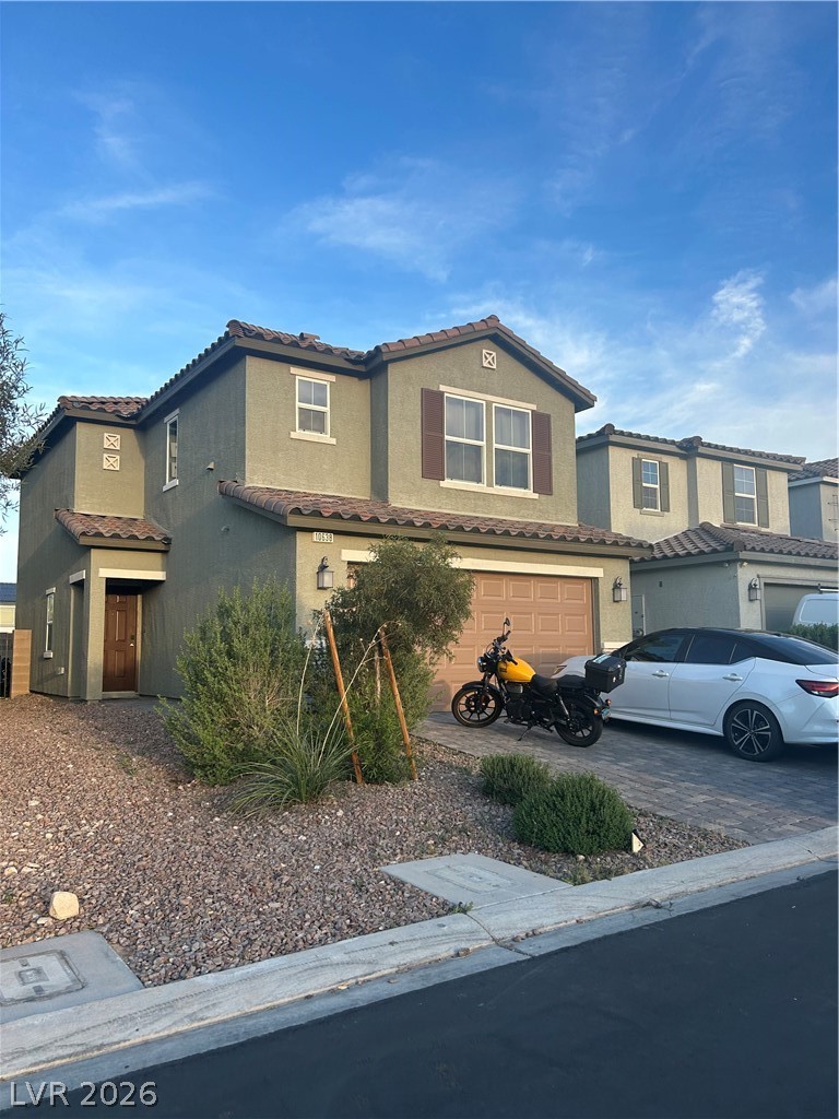 Mediterranean / spanish-style house with a tiled roof, an attached garage, stucco siding, and driveway