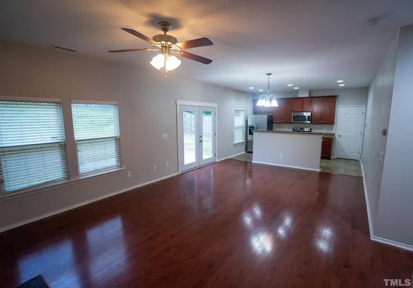 a view of an empty room with a kitchen and wooden floor