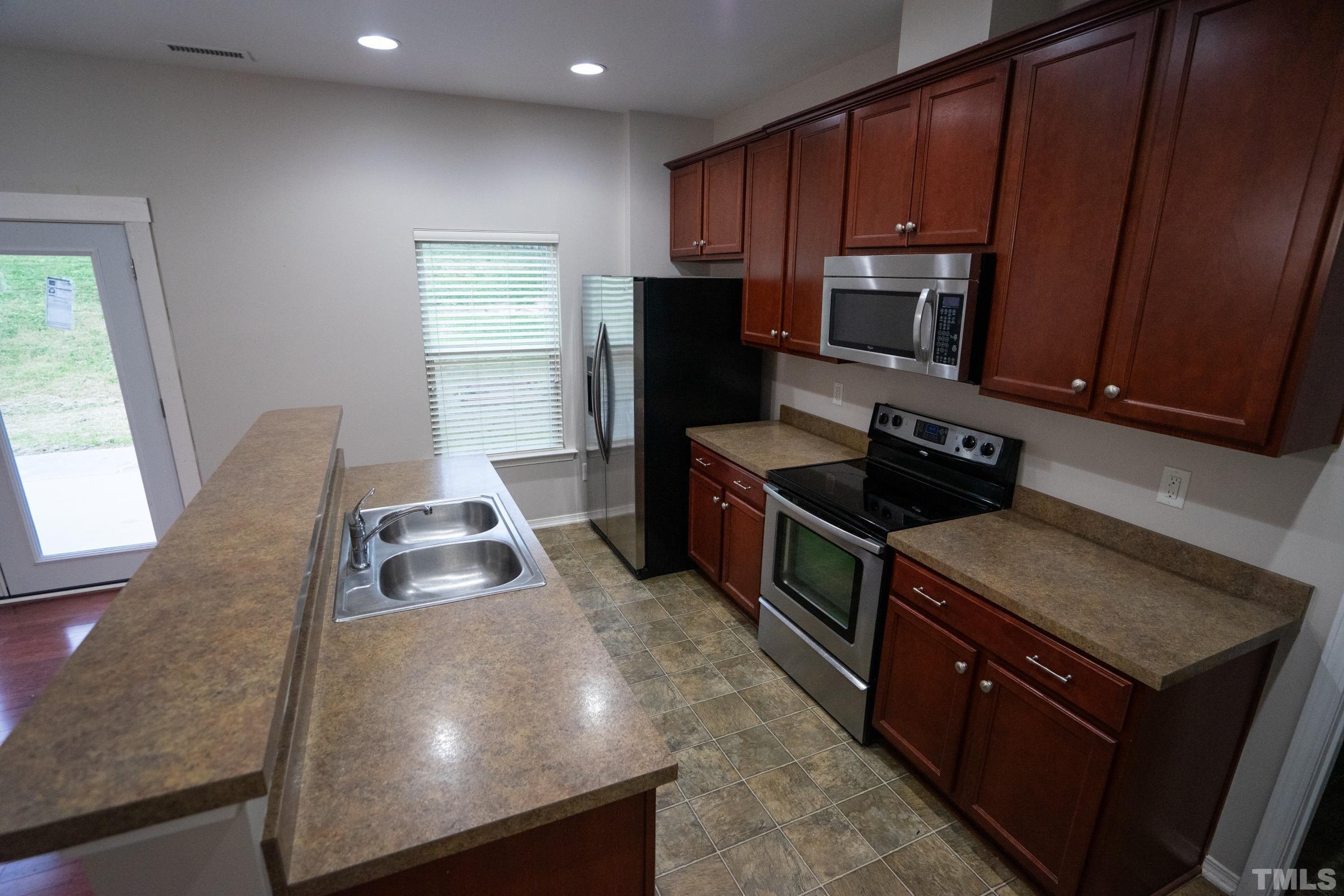 3 Mint Hill Court Durham, NC 27703 - Photo 5 of 19 a kitchen with wooden cabinets a sink and a stove