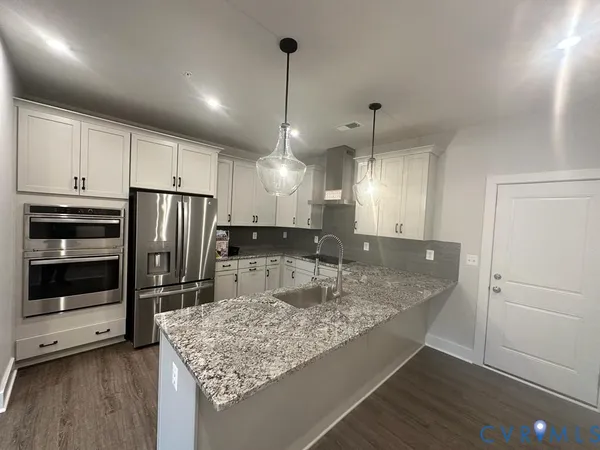 a kitchen with stainless steel appliances granite countertop a refrigerator a sink and a stove