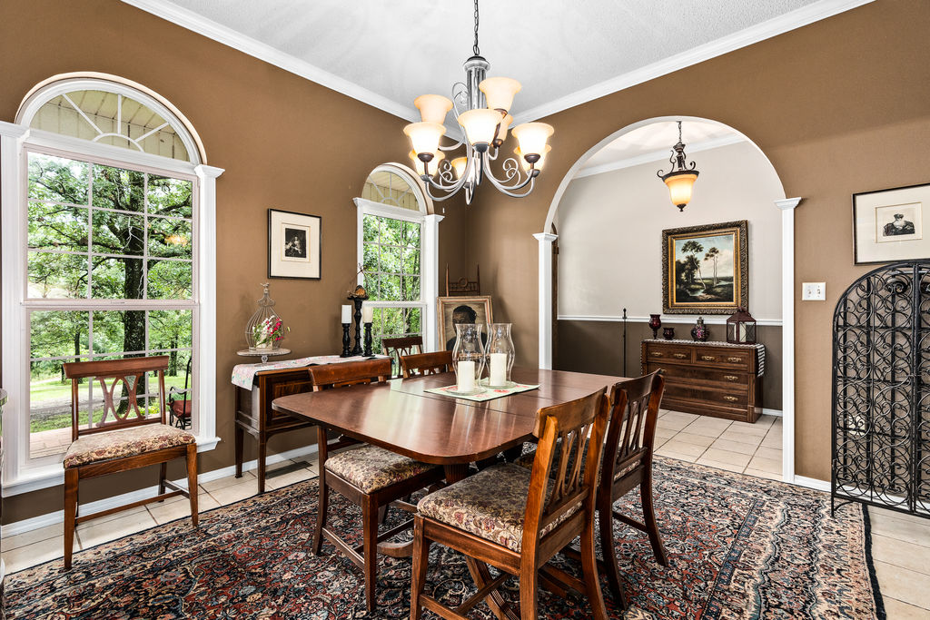 365 Calihan Road Booneville, AR 72927 - Photo 27 of 59 Dining area featuring arched windows with transoms, crown molding, an arched entryway, tile flooring, and a chandelier
