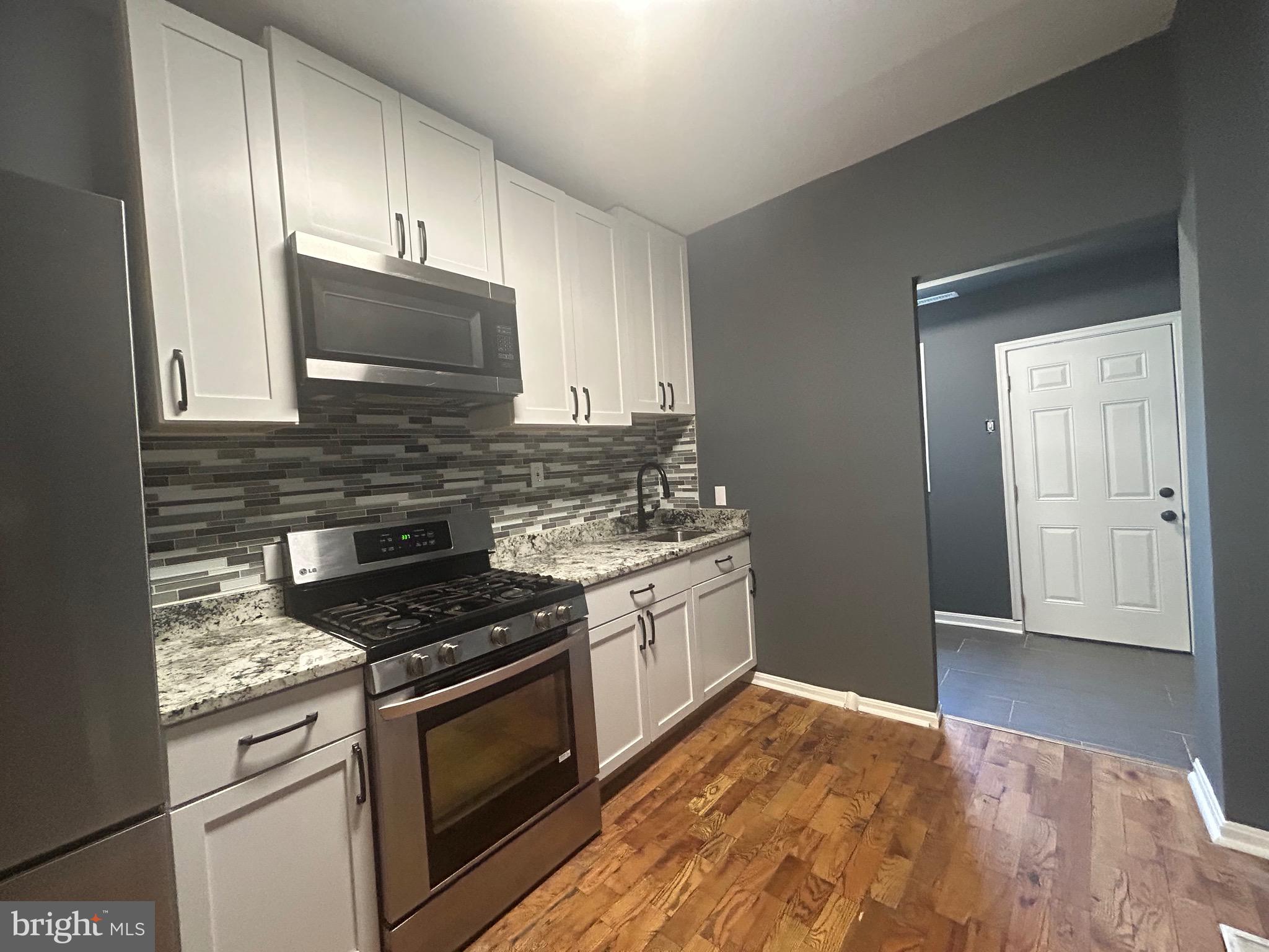 1516 North Mount Street Baltimore, MD 21217 - Photo 29 of 30 a kitchen with granite countertop cabinets stainless steel appliances and wooden floor