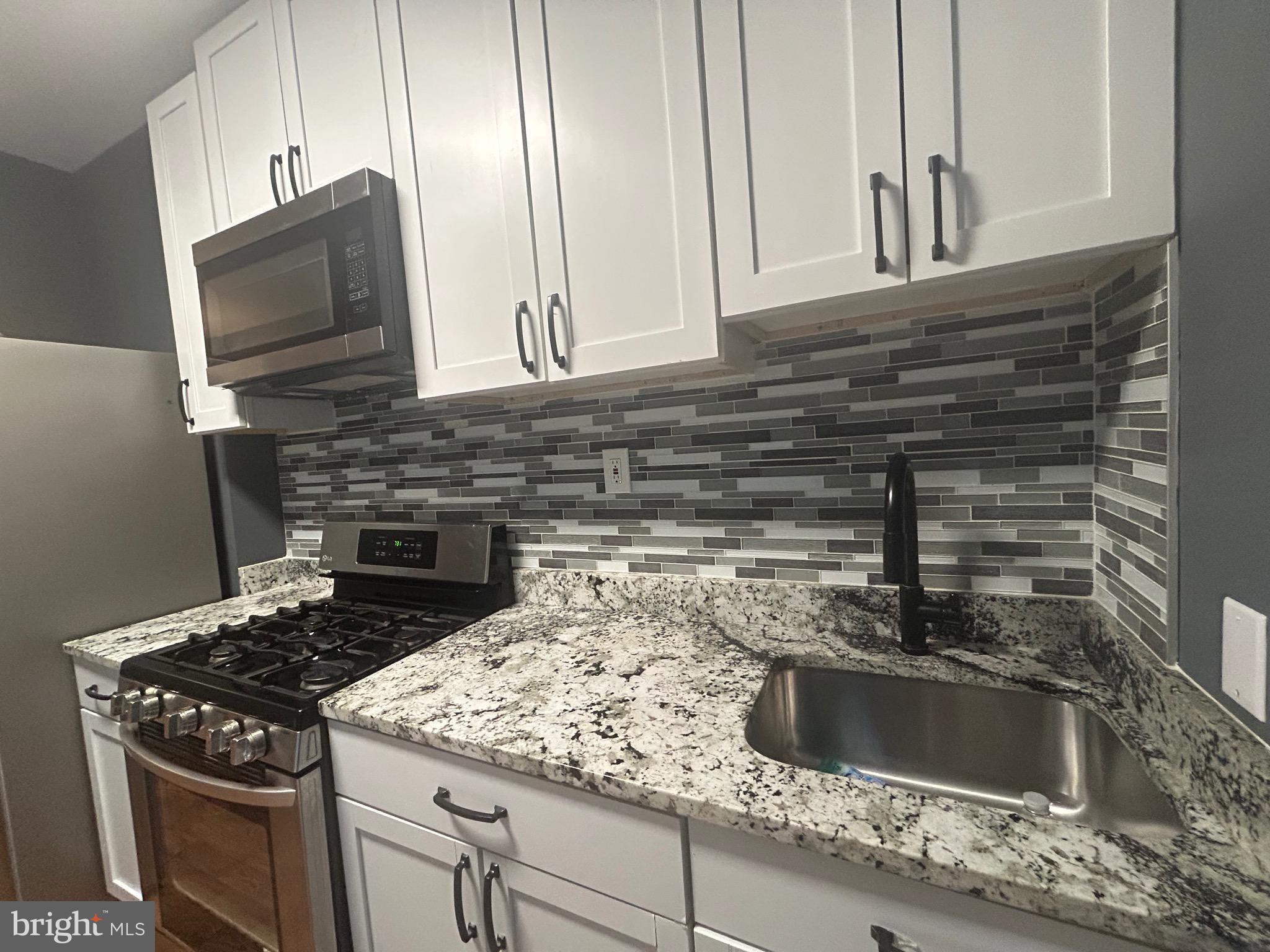 1516 North Mount Street Baltimore, MD 21217 - Photo 4 of 30 a kitchen with granite countertop a sink stove and microwave