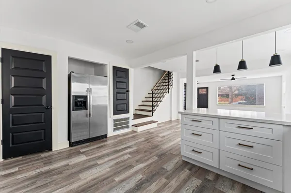a kitchen with stainless steel appliances kitchen island wooden floors and white cabinets