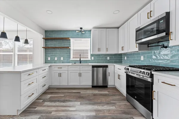 a kitchen with granite countertop white cabinets stainless steel appliances a sink and a window