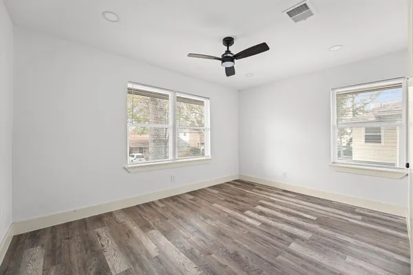 a view of empty room with wooden floor and fan