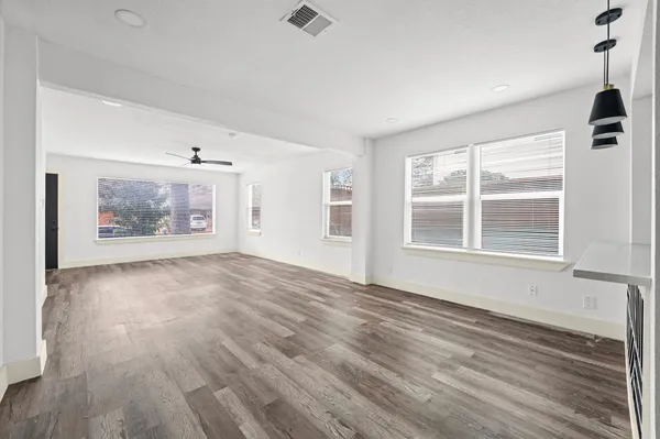 a view of an empty room with a window and wooden floor