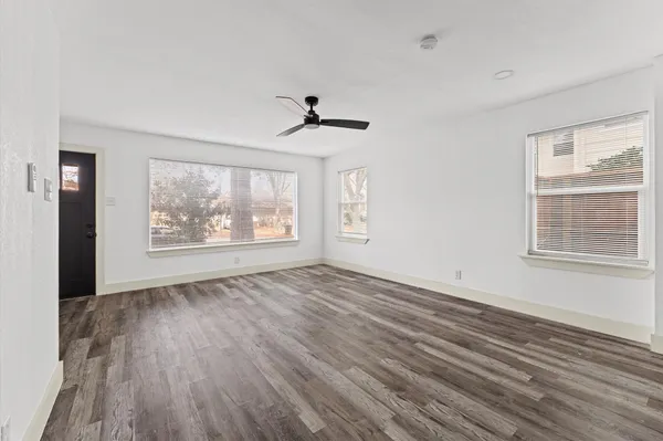 a view of an empty room with a window and wooden floor