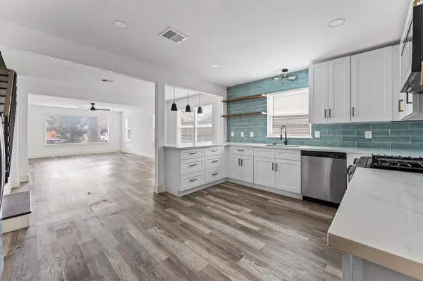 a large kitchen with stainless steel appliances a large counter top a stove and a refrigerator