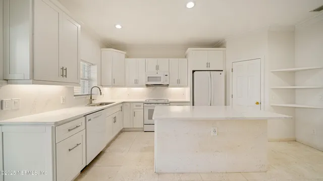 a kitchen with kitchen island white cabinets and refrigerator