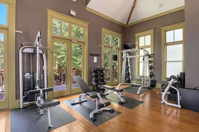 a living room with furniture gym equipment and large windows