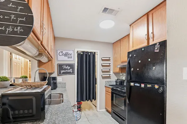 a kitchen with stainless steel appliances granite countertop a refrigerator a stove and a sink
