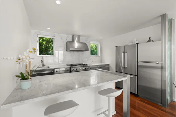a kitchen with granite countertop a table chairs stainless steel appliances and cabinets