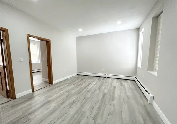 an empty room with wooden floor and entrance