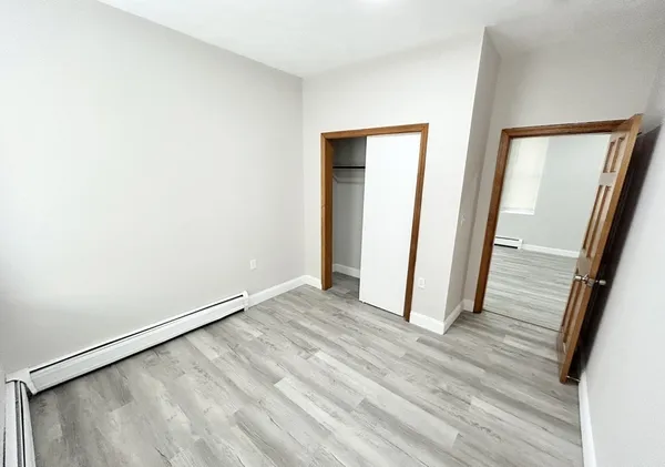 an empty room with wooden floor and mirror