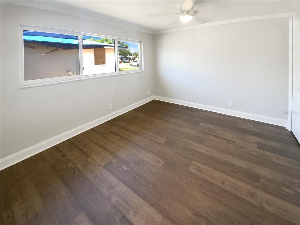 10454 138th Street Largo, FL 33774 - Photo 11 of 35 a view of an empty room with wooden floor and a window