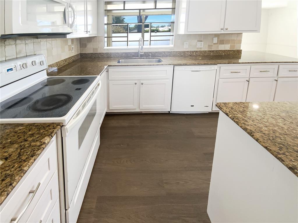 10454 138th Street Largo, FL 33774 - Photo 13 of 35 a kitchen with granite countertop a sink a stove and cabinets