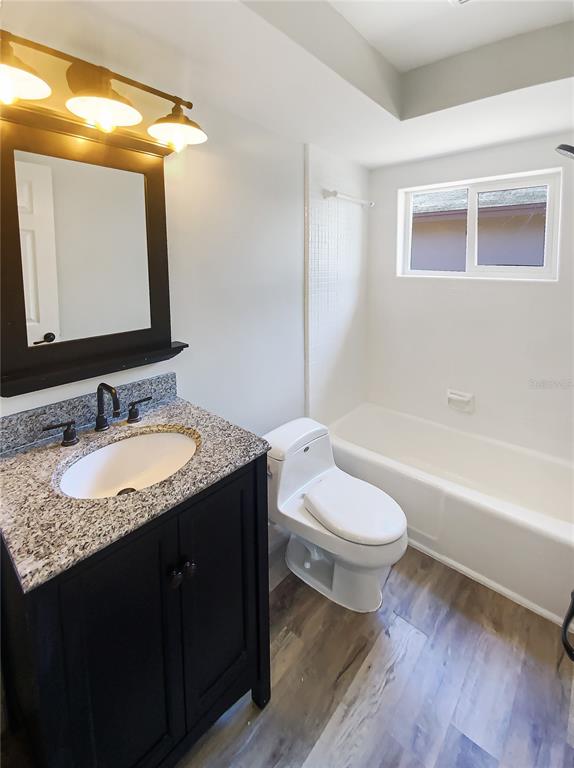 10454 138th Street Largo, FL 33774 - Photo 20 of 35 a bathroom with a granite countertop sink toilet mirror vanity and bathtub