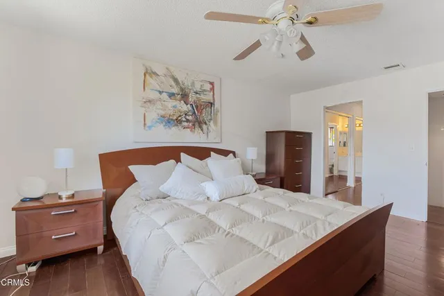 a view of a hallway with wooden floor and a bathroom