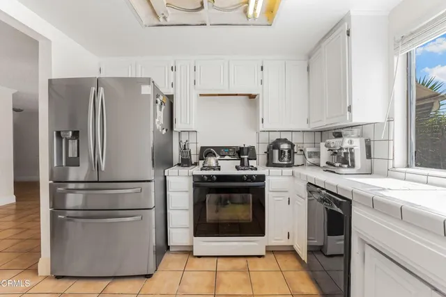 a kitchen with cabinets stainless steel appliances and a window