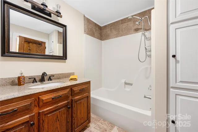 a bathroom with a granite countertop sink a mirror a shower and a bathtub