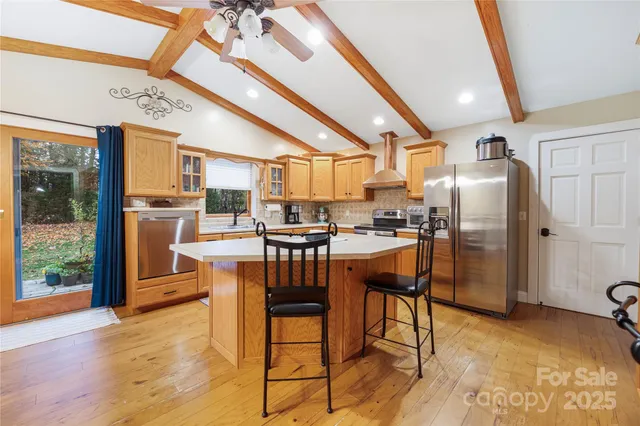 a kitchen with stainless steel appliances granite countertop a refrigerator a stove top oven and a dining table with wooden floor