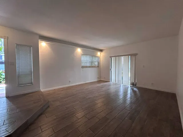 a view of an empty room with window and wooden floor