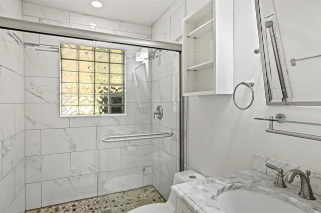 a bathroom with a granite countertop sink a mirror and a shower