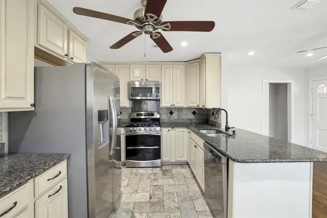 a kitchen with stainless steel appliances granite countertop a sink a stove top oven a counter space and cabinets