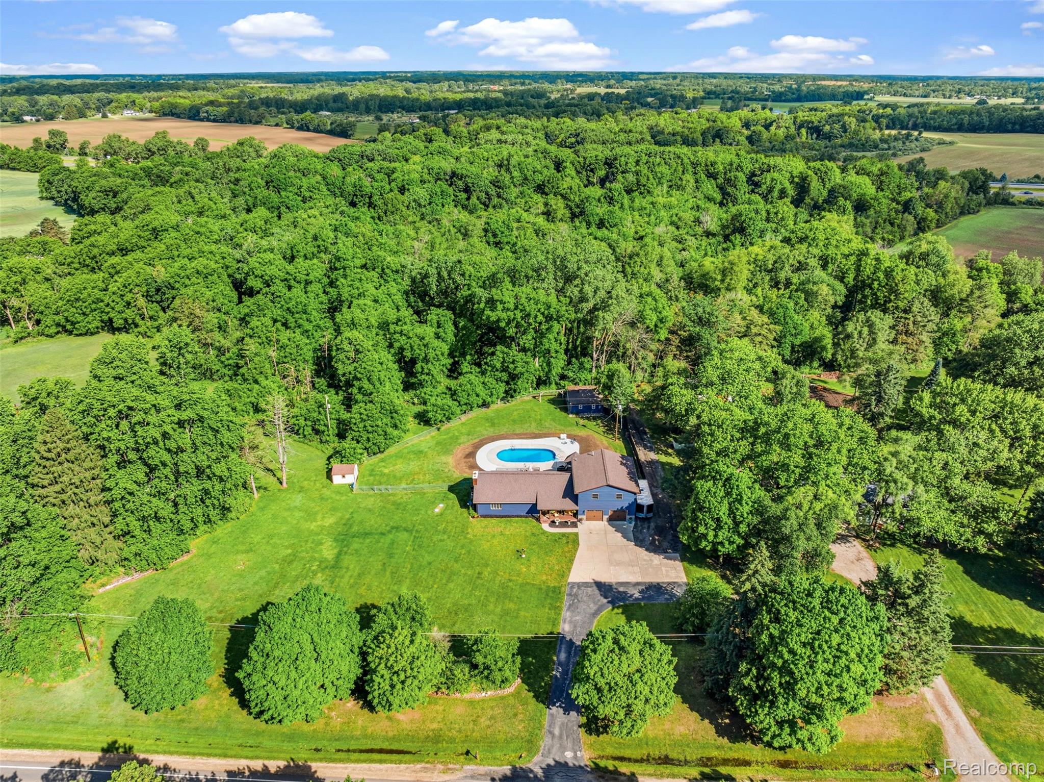 6699 Lansing Road Durand, MI 48429 - Photo 50 of 53 Expansive property featuring a large in-ground swimming pool, a substantial driveway, and surrounding mature trees