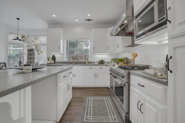 a kitchen with stainless steel appliances granite countertop a sink a stove and cabinets
