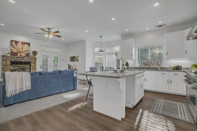 a kitchen with stainless steel appliances granite countertop a stove a sink dishwasher a refrigerator and white cabinets with wooden floor