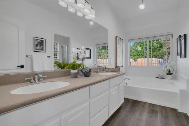 a bathroom with a double vanity sink a large mirror and a bathtub