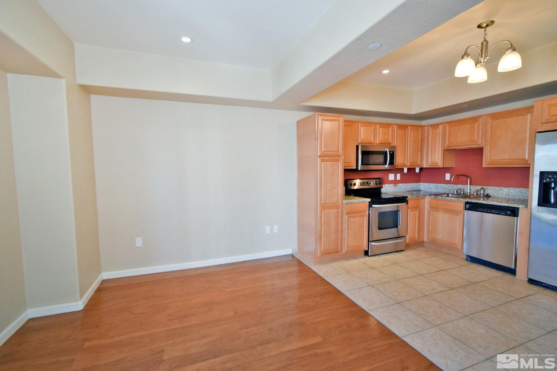 200 West 2nd Street, Unit 1004 Reno, NV 89501 - Photo 7 of 18 a kitchen with stainless steel appliances granite countertop a stove top oven a sink dishwasher and a refrigerator with wooden floor