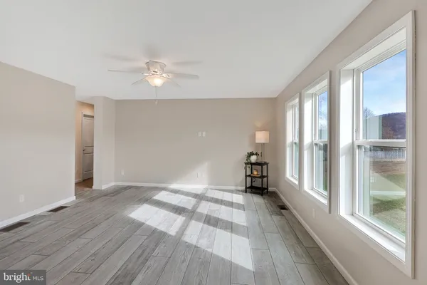 a view of empty room with wooden floor and fan