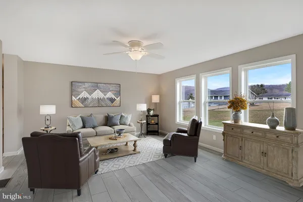 an empty room with a chandelier fan and windows