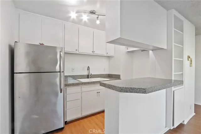 a kitchen with stainless steel appliances granite countertop a refrigerator a sink a stove and white cabinets