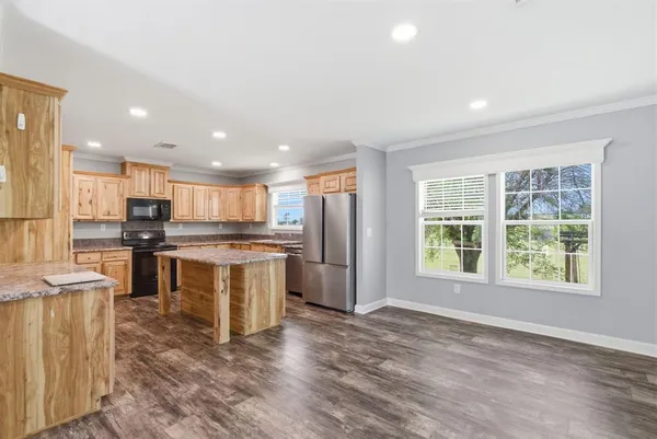 a large kitchen with kitchen island a sink a counter top stainless steel appliances and cabinets