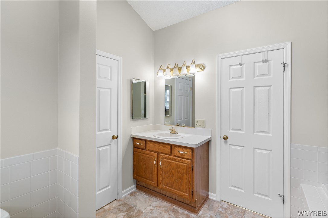 2850 Amsdell Road, Unit 34 Hamburg, NY 14075 - Photo 22 of 33 Vaulted ceilings and classic wall tiling enhance this bathroom space.