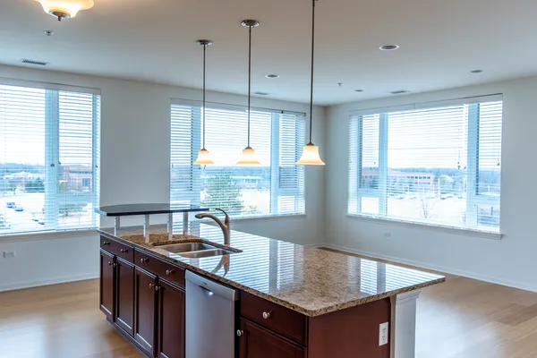 a kitchen with stainless steel appliances granite countertop a stove a sink a refrigerator a center island with wooden floor and cabinets