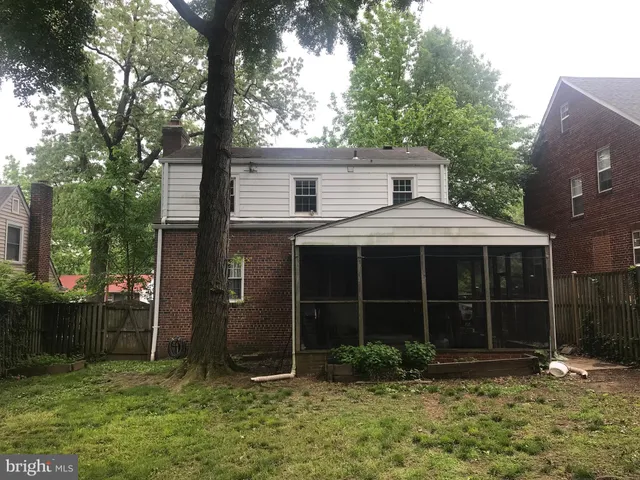 a view of a house with a large window and a yard with plants and large trees