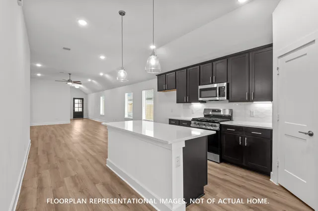 a large kitchen with stainless steel appliances kitchen island granite countertop a stove a sink and a refrigerator