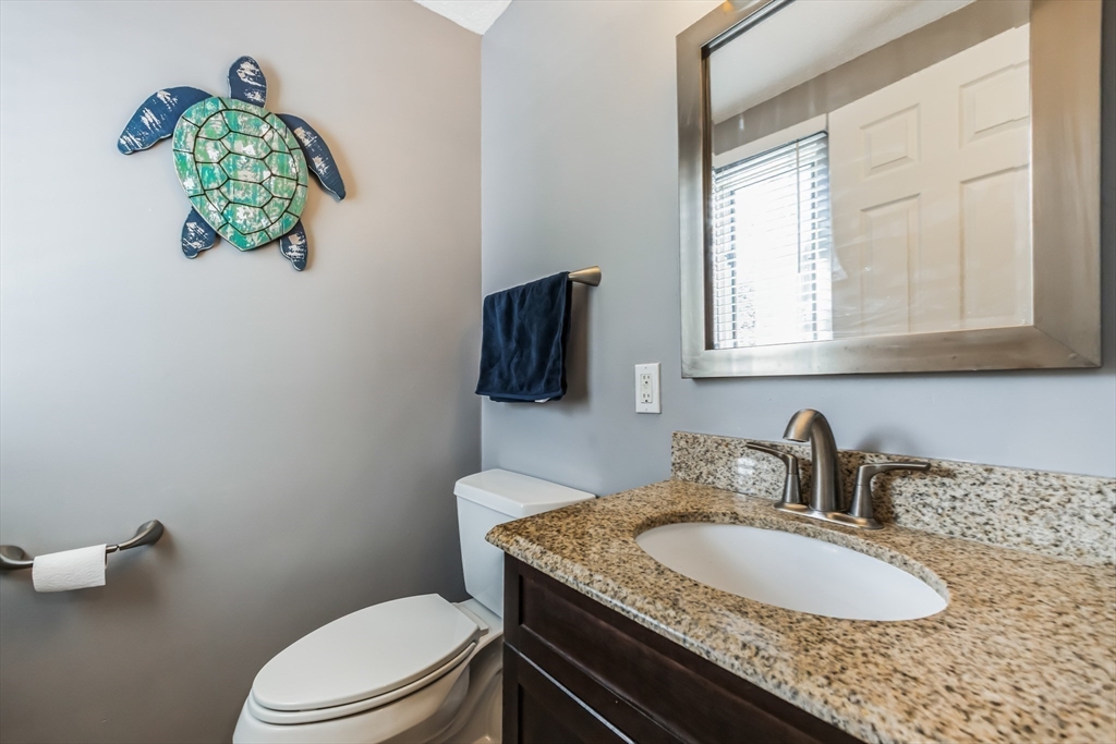 59 Seabury, Unit 59 Hampton, NH 03842 - Photo 12 of 25 a bathroom with a granite countertop sink a toilet and a mirror