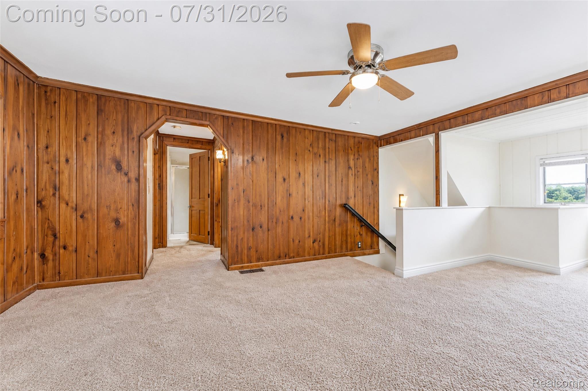5269 Reno Road Manchester, MI 48158 - Photo 57 of 64 Expansive room featuring wood paneling, light-toned carpeting, a ceiling fan with integrated lighting, and a white painted half-wall with a black handrail defining the stairwell
