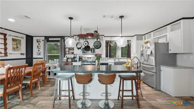 a kitchen with stainless steel appliances granite countertop a stove a sink dishwasher and a refrigerator with wooden floor