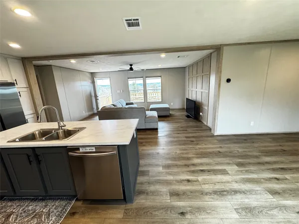 a view of a kitchen island a sink wooden floor and a living room