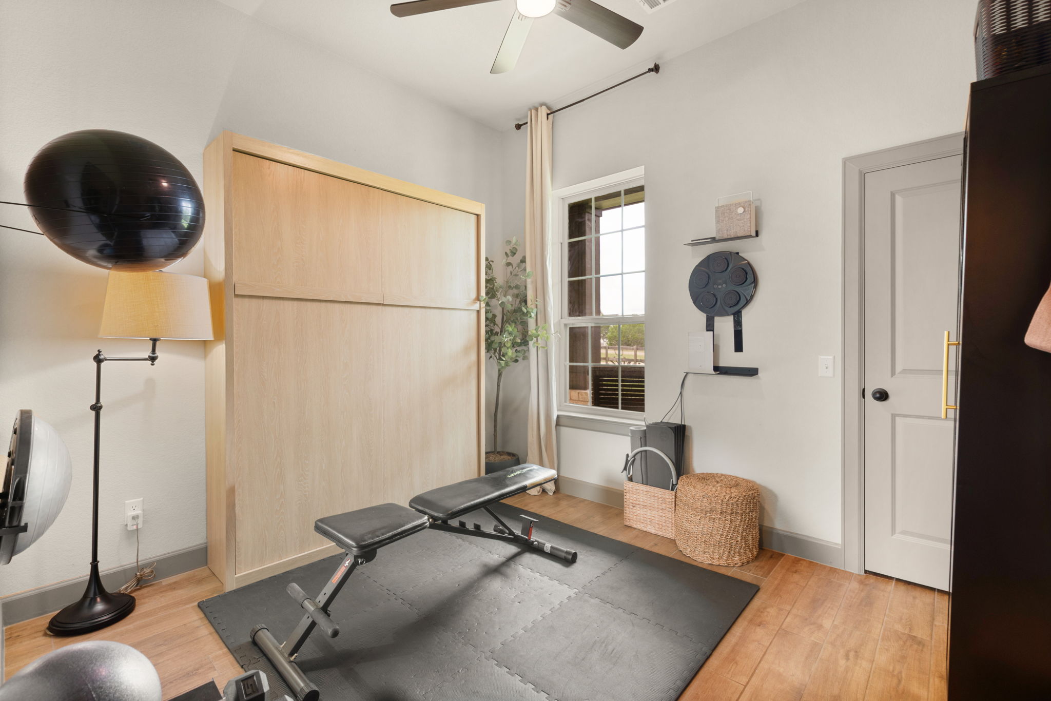 155 Balcones Ridge Way Bertram, TX 78605 - Photo 34 of 37 A versatile space features a hidden wall bed, rich wood flooring, and ample room for fitness equipment.